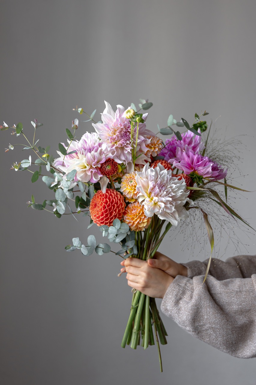 A woman holds in her hand a festive flower arrangement with bright chrysanthemum flowers, a festive bouquet.